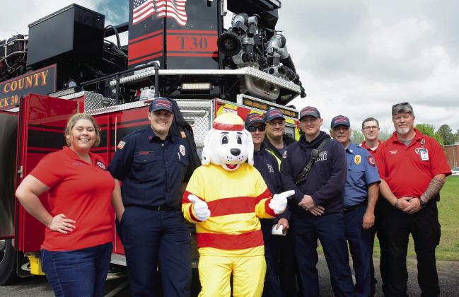 Members of the Putnam County Fire Department line up beside their mascot, “Sparky,” who posed all day with egg hunters while parents took photos. IAN TOCHER/Staff