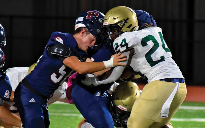 Despite losing his helmet, Gavin Aultman continues to help running back Kumari Thomas push forward for extra yards last Friday night against Aquinas. BRANDON PARK/Staff