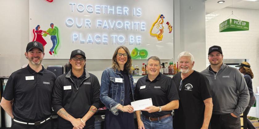 Neighbors Helping Neighbors Executive Director Allyn Rippin (center) accepts a donation from Surcheros owner Kyle Cullars, with several Surcheros employees standing by in support. CONTRIBUTED