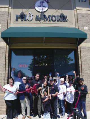 Pho & More co-owner Marino Graf (with scissors) stands with his wife, Summer, her father, John Nguyen, and the couple’s daughter while friends and employees help them celebrate during a ribbon-cutting ceremony hosted by the Eatonton-Putnam Chamber of Commerce. IAN TOCHER/Staff