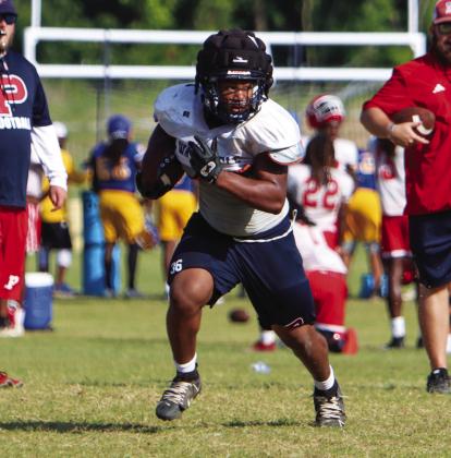 Elijah Dunn carries the ball for Putnam County during a padded camp in Eatonton ahead of the 2024 season. LANCE McCURLEY/ Staff