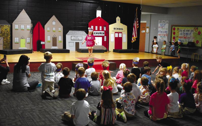 Classmates watch K-4 student Macey Duvall showing off her shirt that states, “100 Days Sprinkled with Fun.”