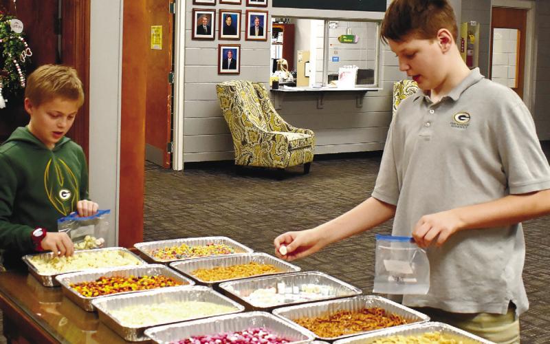 Fourth-graders Hayden Ferguson (left), and Van Wells load up their snack bags with 100 items.
