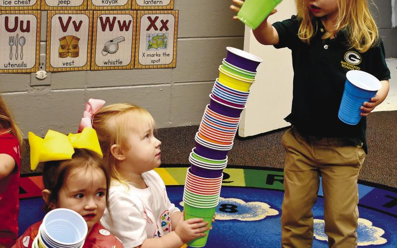 Playing with 100 cups, pre-K students Blayke May and Miller Van Dusen build a tower, while Farryn Pinkerton is content with her own stacking project.