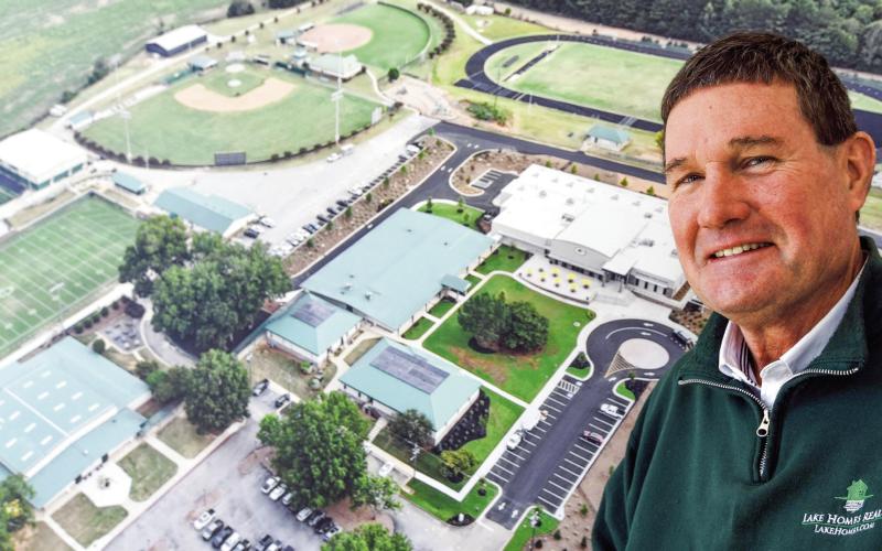 Gatewood’s Jeff Decker stands beside a large aerial photograph of the school’s 30-acre complex, much of which he had a hand in helping to develop over his nearly 13 years in Eatonton. IAN TOCHER/Staff