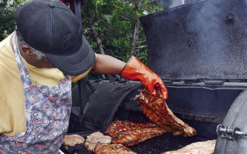 Curt Solomon of Bullard’s BBQ in Warner Robins checks a rack of ribs during Eatonton’s “Peg Leg” Howell BBQ &amp;amp; Blues Festival. GORDON COLUMBINE/Staff