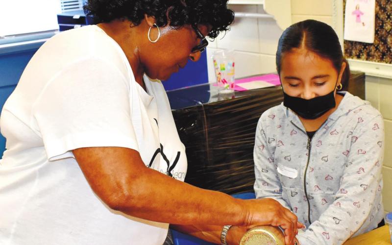 Teacher Janice Hurt adds glitter to Jennifer Sanchez’ jar. LENA HENSLEY/Staff