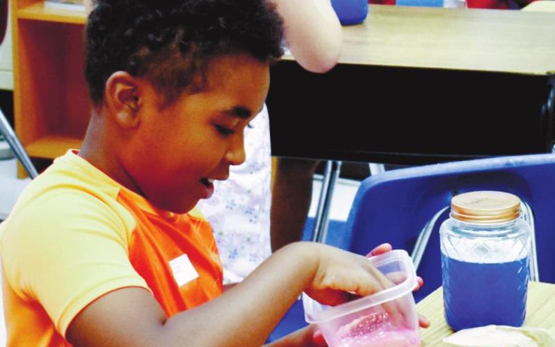 Landen Simmons is smiling playing with his slime. LENA HENSLEY/Staff