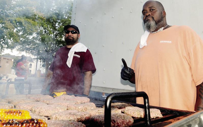Brandon Brown (left) and Roger Bond of the Rock Eagle cafeteria crew had cheeseburgers and corn-on-the-cob on the grill at Taste of Eatonton. LEIGH LOFGREN/Staff