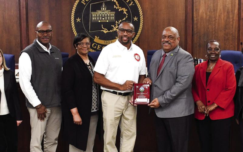 Prior to last Tuesday’s council meeting, retired Eatonton Fire Department Deputy Chief Carl Buckner, Sr. (center, white shirt) was presented with an official plaque recognizing “25 years of untiring service to the citizens of Eatonton,” by Mayor John Reid, EFD Chief Jamey Williamson, and all city council members. IAN TOCHER/Staff