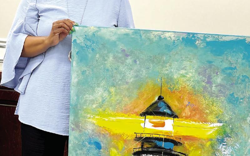 Putnam County Board of Education member Doris Clemons accepts a painting after her name was drawn during a raffle at the Putnam County Board of Education meeting. Clemons announced she would donate the artwork to the PCBOE. ALIVIA BLANTON/ Staff