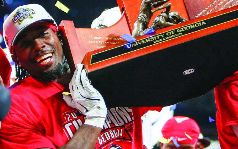 A Georgia player holds up the SEC Championship trophy on the stage after the game. LANCE McCURLEY/Staff