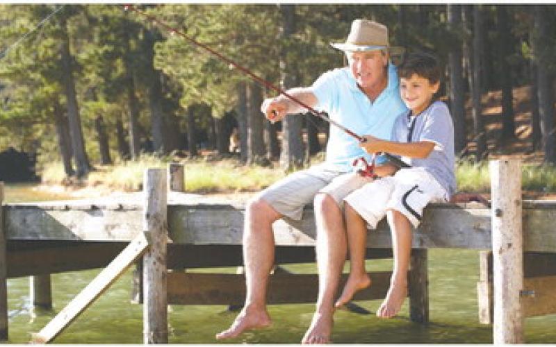 Dad showing his son how to reel in a fish. STOCK PHOTO
