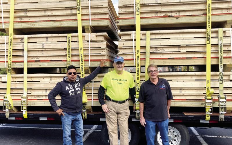 Steven Britton (right) prepares to travel to North Carolina after he and Dick Forrester (center), team coordinator of the Sheds of Hope Ministry, and lift operator Romeo Chavez help finish load the six prepackaged sheds. T. MICHAEL STONE/Staff