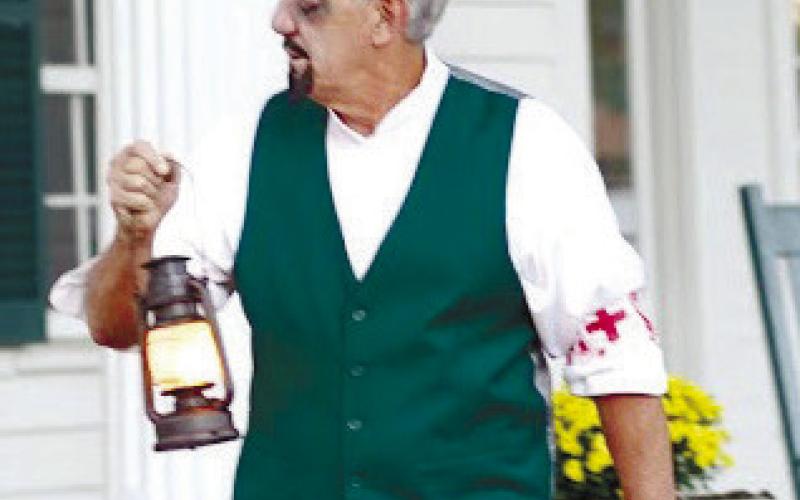 An actor portraying Dr. Blackwell carries a lantern in front of the historic Blackwell home, speaking to Haunted Eatonton tour guests. GENE GARCIA/Contributed
