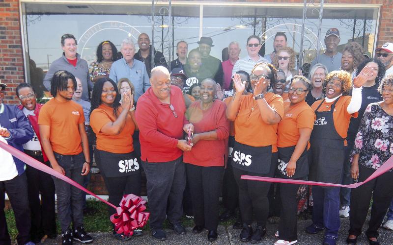 Surrounded by family and friends at high noon on Saturday, Eatonton Mayor John Reid with his wife and city councilmember Janie Reid (center), cut the ribbon to Sips, their new coffee shop and restaurant at 104 E. Marion St., in downtown Eatonton. IAN TOCHER/Staff