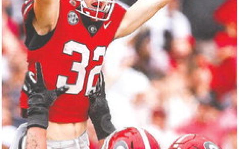 Georgia offensive lineman Tate Ratledge (77) holds up Cash Jones (32) after he scored a touchdown in the fourth quarter of the Bulldogs win over South Carolina last week. TONY WALSH/UGA Athletics