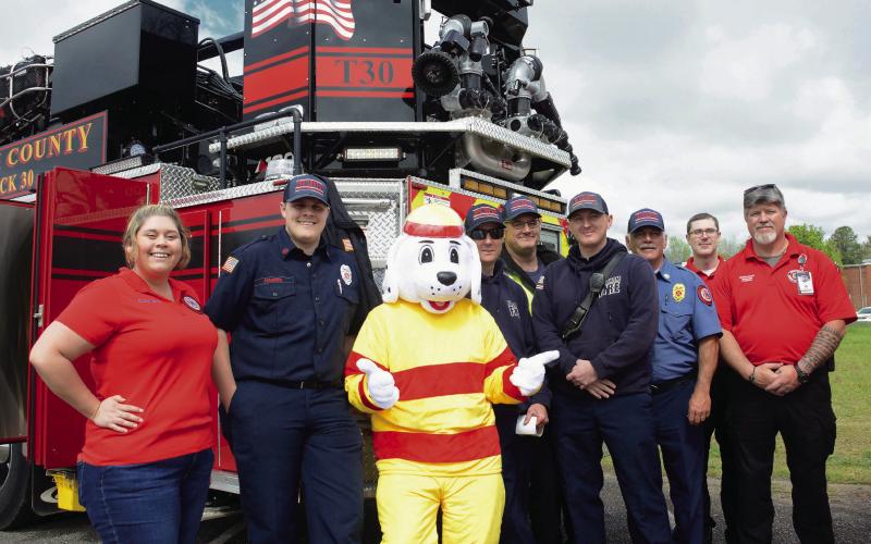 Members of the Putnam County Fire Department line up beside their mascot, “Sparky,” who posed all day with egg hunters while parents took photos. IAN TOCHER/Staff