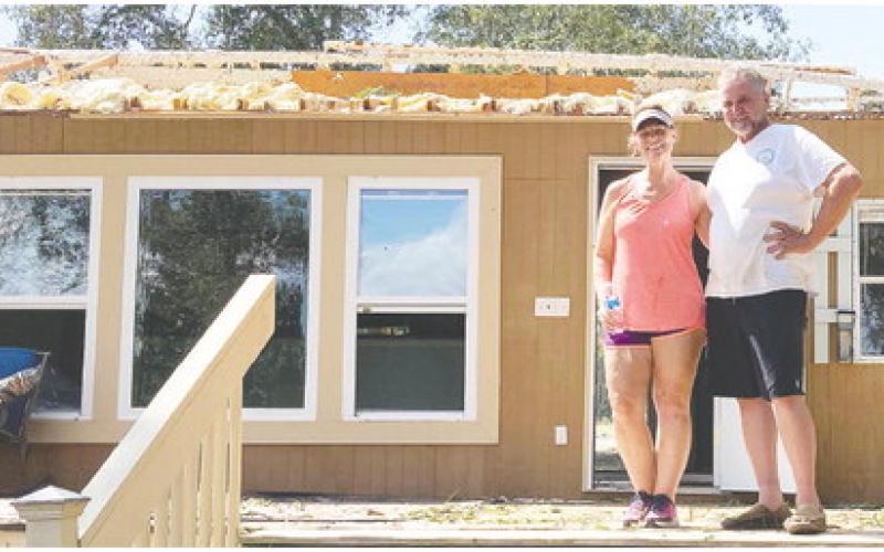 Allen and Lisa Jordan said they can still smile even though their weekend home was ravaged by a storm because they are grateful for safety and the help of their friends and neighbors. The back porch where they are standing, was completely roofed and furnished before the storm, believed to be a microburst, ripped the roof away. LYNN HOBBS/Staff