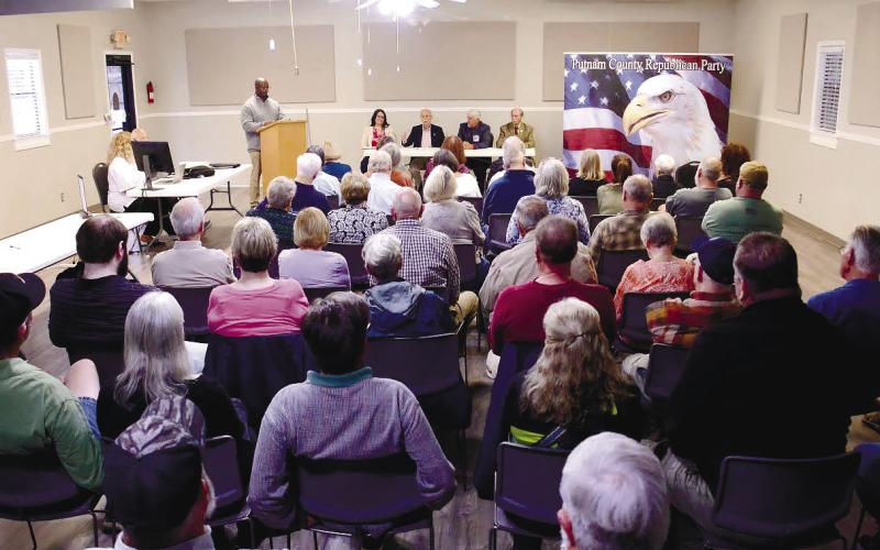 A full house faced Putnam County District 3 commissioner candidates last Thursday at Lake Oconee Lutheran Church Community Center, where former candidate Charles Trumbo (at podium) served as emcee for the event.