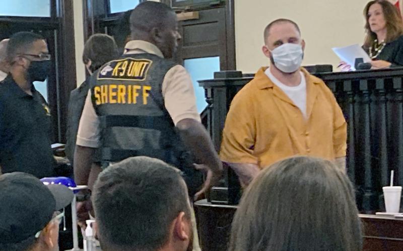 Christopher Demmon looks at and speaks to the victim’s family as he is escorted out of the courtroom.