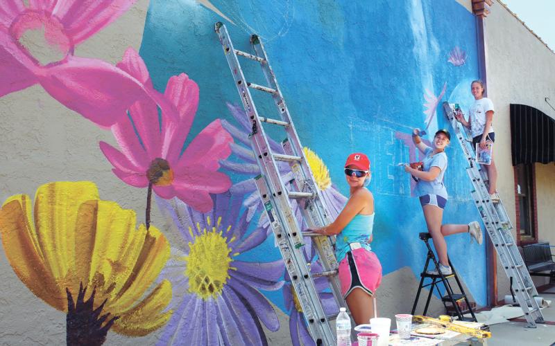 Painters work on a new mural in downtown Eatonton during the Dairy Festival, bringing color to the side of the building that houses Nails by Aaron at the corner of North Jefferson Avenue and Marion Street. IAN TOCHER/Staff