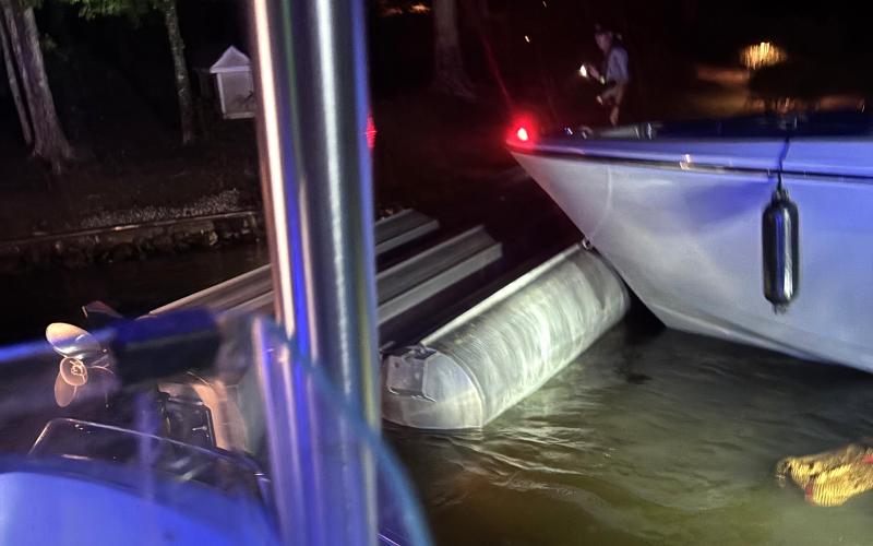The capsized tritoon is being pushed by Putnam County Sheriff’s boats to the shore after a fireworks show on Lake Oconee July 4. (Contributed)
