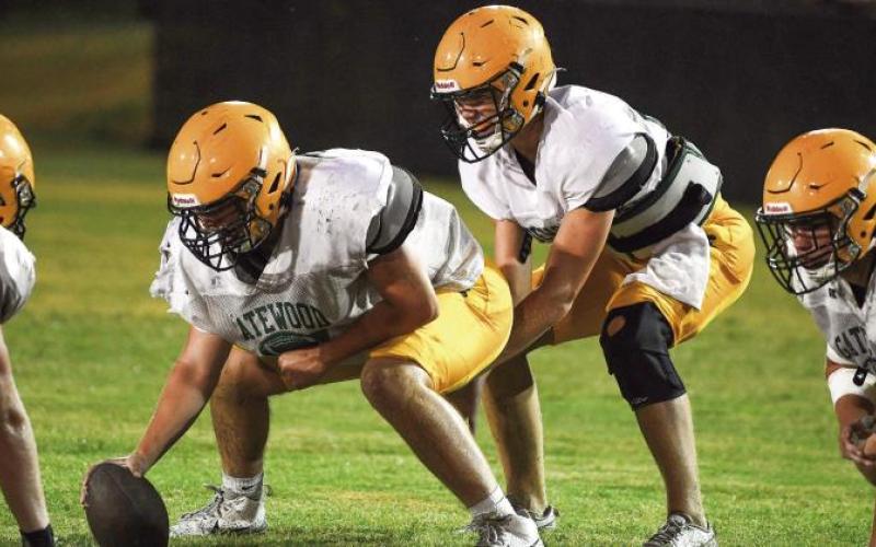 Gatewood sophomore quarterback Blake Brannen takes a snap from junior center Drew Burke during pre-season practice at Gatewood’s Sammons Field in Eatonton. IAN TOCHER/Staff
