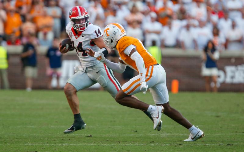 Georgia quarterback Gunner Stockton (14) scrambles out of the pocket past a Tennessee defensive back. LANCE McCURLEY/Staff
