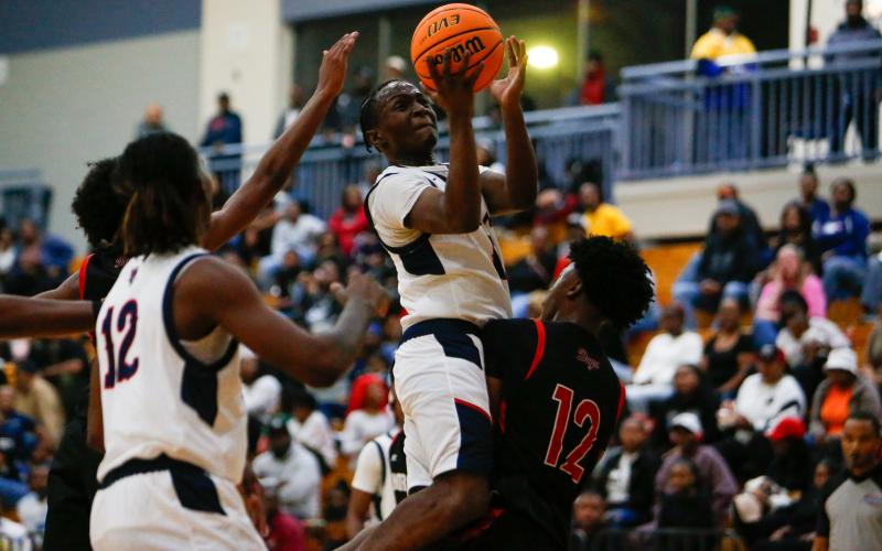 Putnam County senior guard Tamaud Woodson (0) attempts to make a basket over the top of Morgan County forward Trey Carter (12). LANCE McCURLEY/Staff