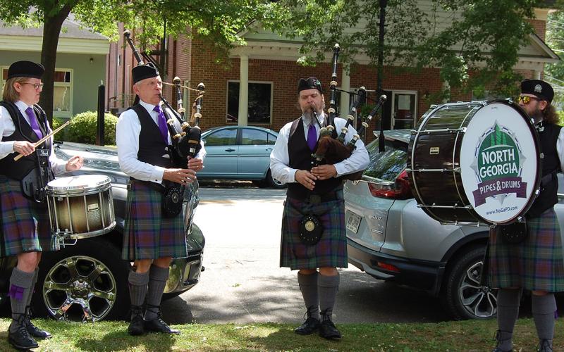 Bagpipers and drummers playing outside as attendees arrive.