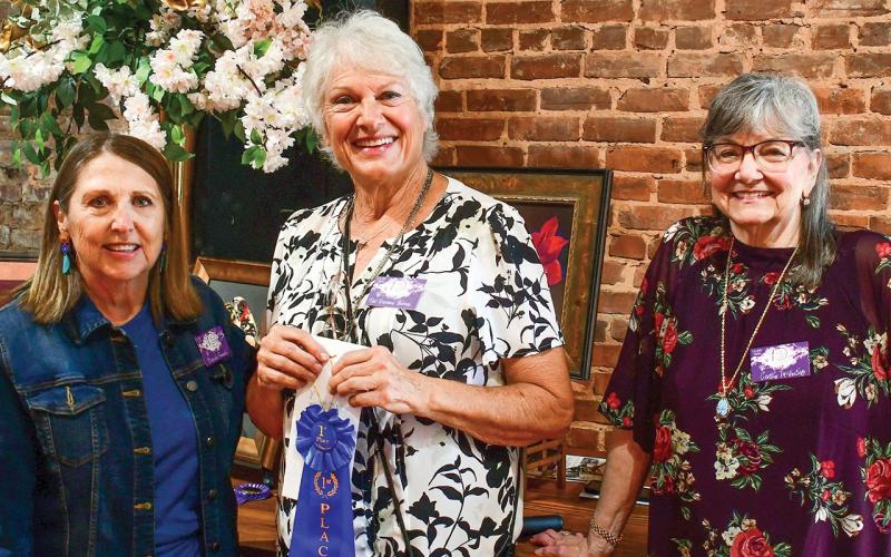 Artist Pat DeVane Burns (center) accepted the blue ribbon, signifying her first-place finish in the 10th annual Lake Country Juried Art Show, from show judge Brenda Pinnick (left) and event co-chair Cathy McIntire.