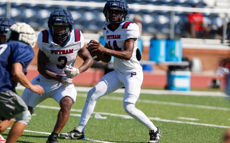 Putnam County quarterback Caleb Reeves (14) drops back in the pocket with running back Elijah Dunn (3) providing pass protection during a padded camp in Eatonton last month. LANCE McCURLEY/Staff