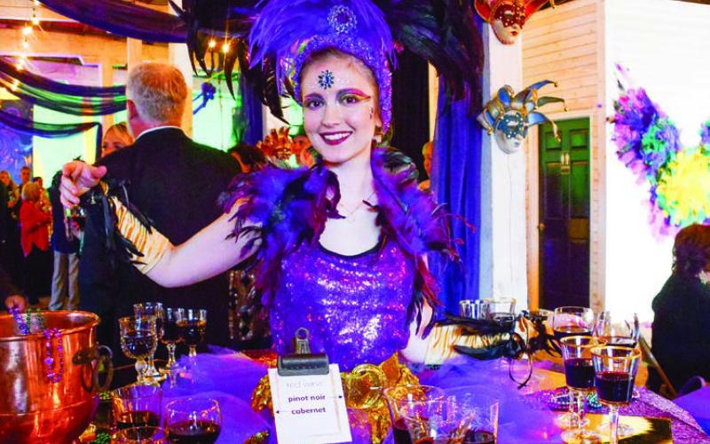A performer at one of two “living tables” provided wine and ArtiGras beads to guests at The Livery before the party moved next door to Barrel 118. IAN TOCHER/Staff