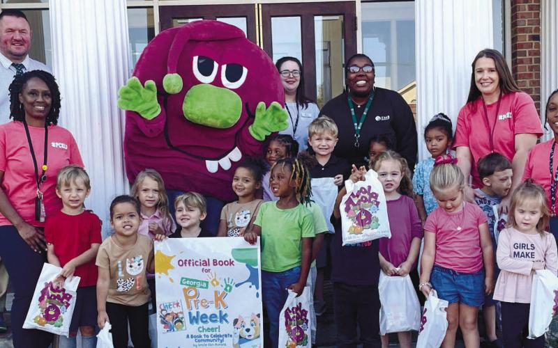 L to R: Lurner O. Benton IV, PreK teacher Jennifer Mitchell, FMB mascot Moola-Moola, Taylor Addison, Beth Sharp, Tawana Ellison, Mrs. Reva Droltz and Miss Marquita Stubbs posed with their class at downtown Eatonton’s Farmers and Merchants Bank. CONTRIBUTED