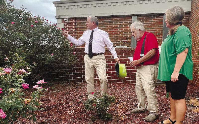 Putnam County Manager Paul Van Haute (left) revealed a pink rose bush, planted in memory of county employee Deborah Rogers, to Charles Rogers and Dee Burks, Rogers’ surviving husband and daughter.