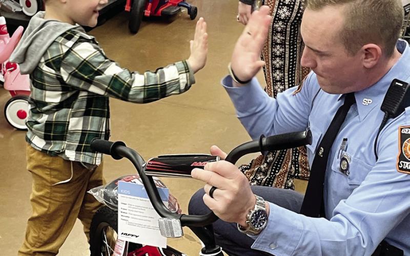 Oliver Philippe, 6, spontaneously gives GSP Trooper Derek Snead a high five after he picked out a new bicycle. LYNN HOBBS/Staff