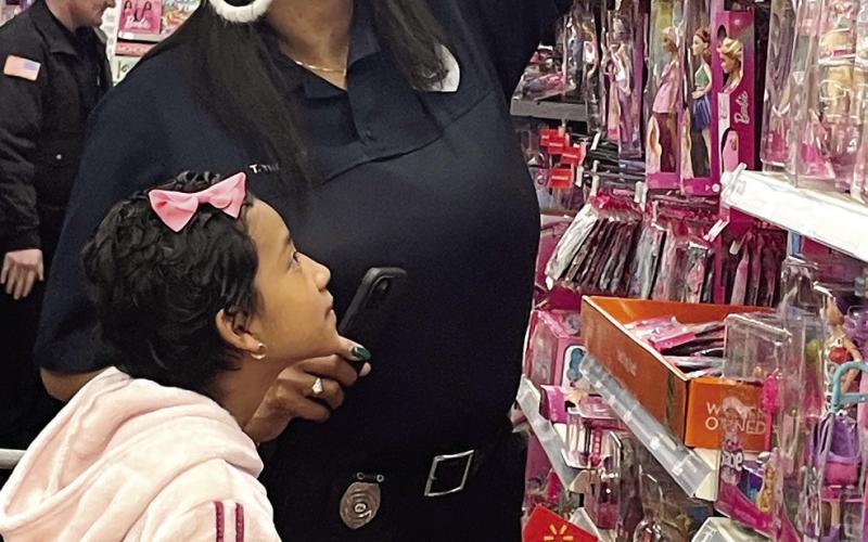 Eatonton Police Department's Tonya Thomas helps Mia Lopez, 10, reach a toy off the top shelf. LYNN HOBBS/Staff
