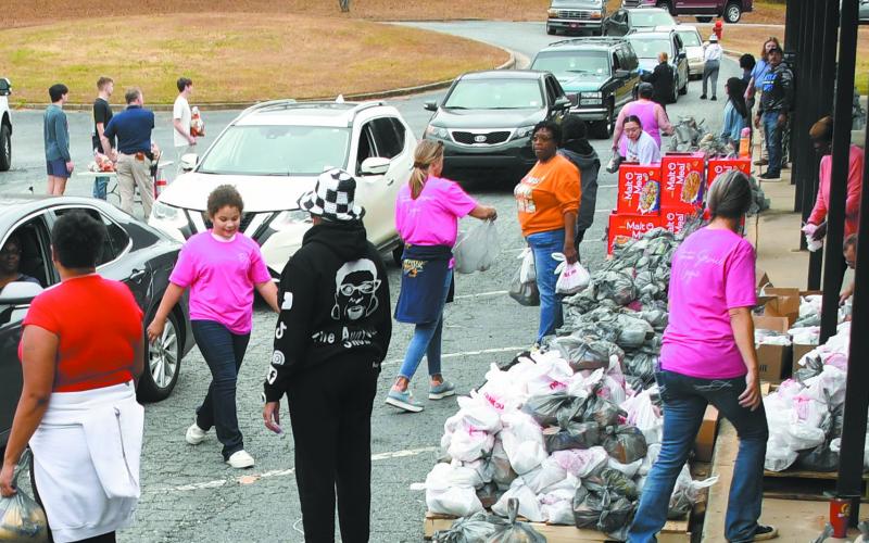 A steady stream of cars rolled through the parking lot of Eatonton’s old Putnam County Elementary School on Saturday morning as volunteers handed out thousands of pounds of food to grateful recipients. IAN TOCHER/Staff