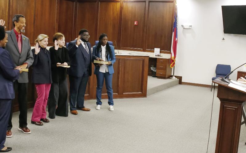 With Mayor John Reid seated behind them (far left), starting second from left, Councilmembers James Gorley, Teresa Doster, Mylle Mangum, and new addition Fredrick Lowe face Putnam County State Court Judge Michael Gailey (far right), who administered the Jan. 6 swearing-in ceremony at the county administration building. IAN TOCHER/Staff