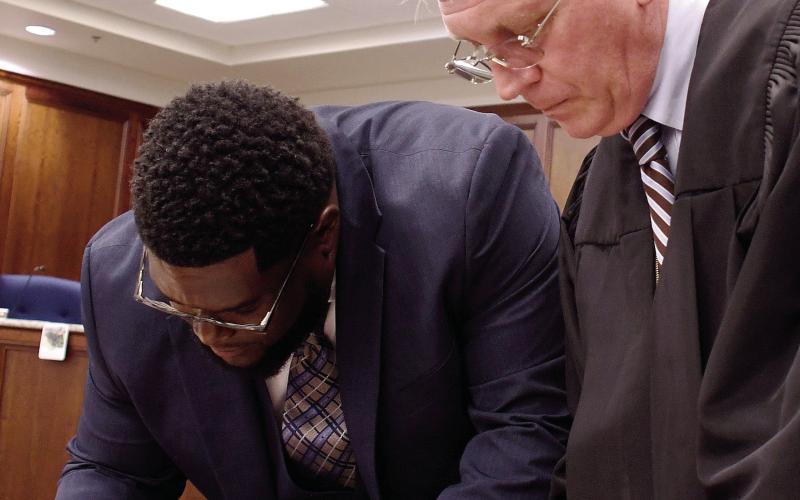 New Eatonton Ward 3 Councilman Fredrick Lowe (left) signs documents after being sworn in by Putnam County State Court Judge Michael Gailey. IAN TOCHER/ Staff