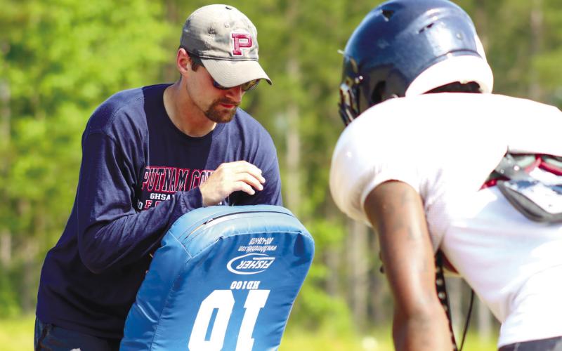 Beasley (left) coaches up a Putnam County player during blocking drills at practice this past spring. LANCE McCURLEY/Staff