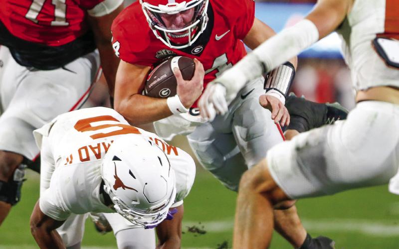 Georgia quarterback Gunner Stockton (14) runs over Texas defensive back Malik Muhammad (5) on his way to pick up a first down. LANCE McCURLEY/Staff