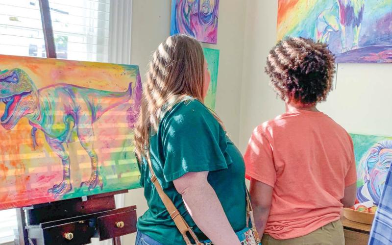 Two attendees view “Chromatic King” (right) that depicts a lion looking out beyond where it stands.