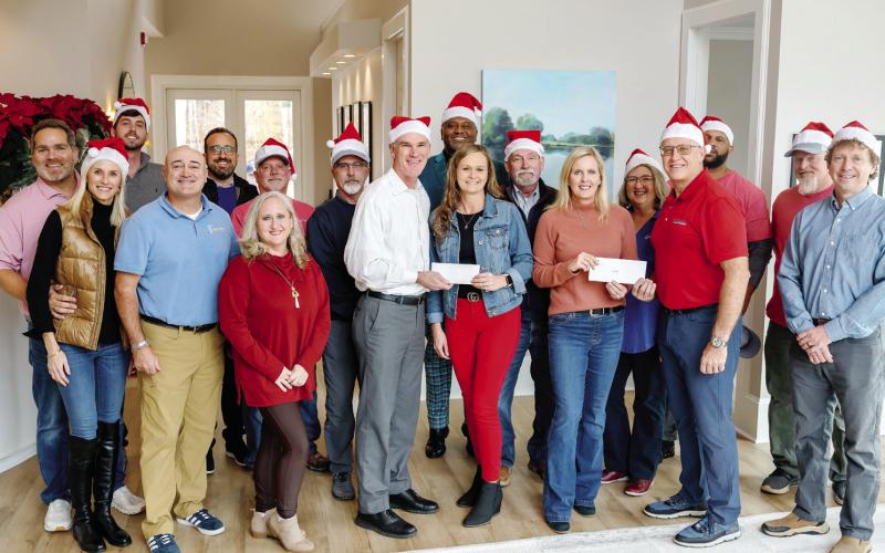 Luxury Lake Oconee’s Ted Baker (center, white shirt) and Weidmann Remodeling’s Dan Weidmann (right, red shirt) present Lake Oconee Area Builders Association’s Wendy Daniel and Christy Kimbrough, alongside team members from both offices, with donations to support LOABA’s Christmas Outreach Drive. CONTRIBUTED
