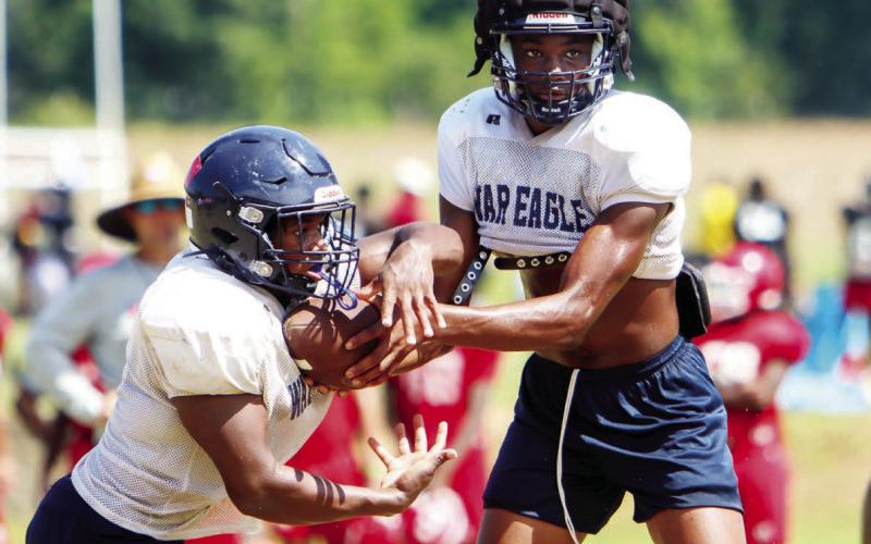 Putnam County senior quarterback Jamarion Robertson hands the ball off to sophomore running back Elijah Dunn during a scrimmage against Hawkinsville last week. (LANCE MCCURLEY/Staff)