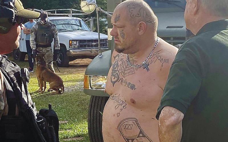 Andy Kirk Davis, center, being held by Putnam County Sheriff’s Lt. Harry Luke, right, is questioned by Butts County Sheriff’s detectives outside Davis’ Putnam County home in 2020. CONTRIBUTED/PCSO