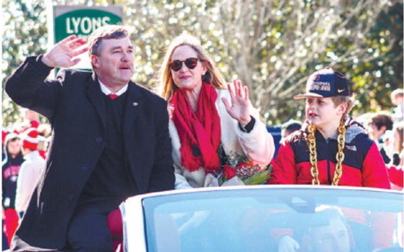 Georgia head coach Kirby Smart (left), his wife, Mary Beth (center, and their son, Andrew (right), ride in the back of a convertible while waving at fans during Saturday’s parade. LANCE MCCURLEY/Staff