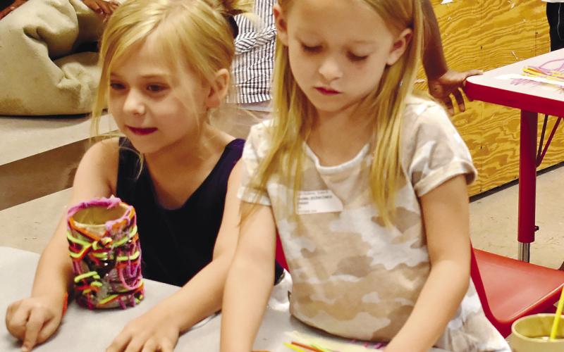 Josie Holder and Cadence Reid weave pipe cleaners together to decorate their pencil holders. LENA HENSLEY/Staff