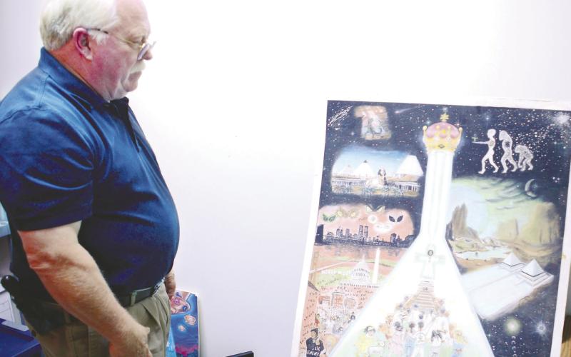 Sheriff Howard Sills looks over an old poster in a storage room filled with Nuwaubian materials and evidence at the Putnam County Sheriff’s Office in Eatonton. IAN TOCHER/Staff